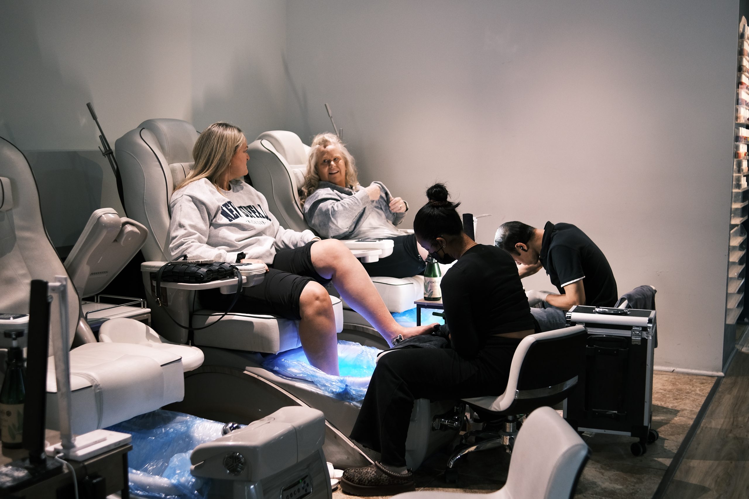 Relaxing foot spa with clients receiving pedicures in a modern nail salon environment.