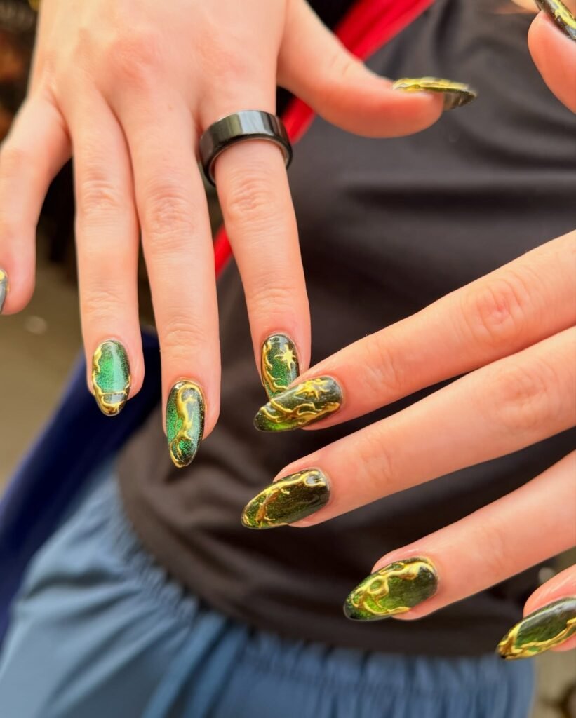 An executive hand presentation featuring emerald cat eye and gold chrome nail designs